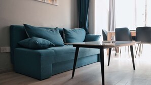 Un salon moderne avec un canapé de couleur turquoise, une table basse en bois et un coin repas avec des chaises.