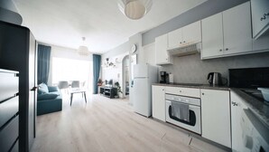 Une cuisine moderne avec des meubles blancs, un four encastré et une cuisinière noire.