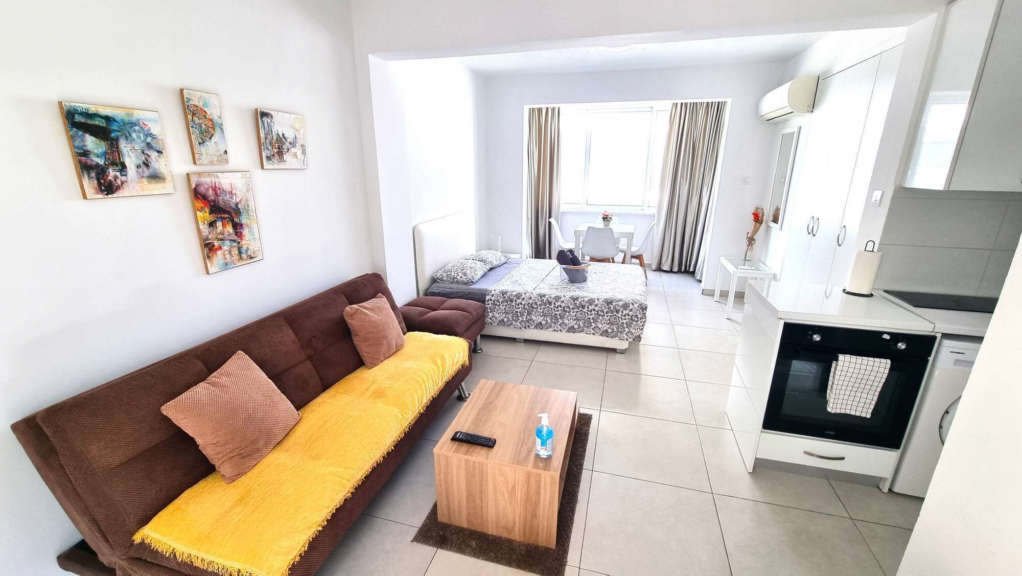 Een modern appartement met een bank, een bed, een keukenhoek en een eettafel.