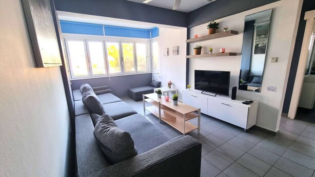 Een moderne woonkamer met een bank, een salontafel, een televisie en planten op planken.