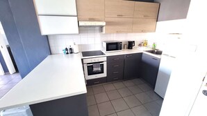 Een kleine keuken met een magnetron, oven en spoelbak.