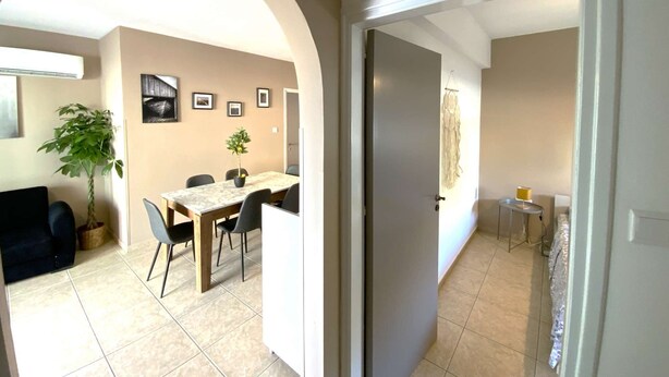 Un'area pranzo con tavolo e sedie, una pianta in vaso e quadri appesi al muro.