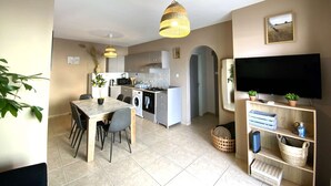 Una cucina moderna con zona pranzo, televisore, angolo living con televisore ed scaffali.