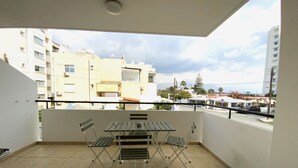 A balcony with a table and chairs, a view of buildings, and a tiled floor. - 2Br Apt - 5mins walk to the Beach + Netflix access (Larnaca)