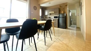 A modern kitchen with a dining area, including a table and chairs, and a view to the outside. - 2Br Apt - 5mins walk to the Beach + Netflix access (Larnaca)
