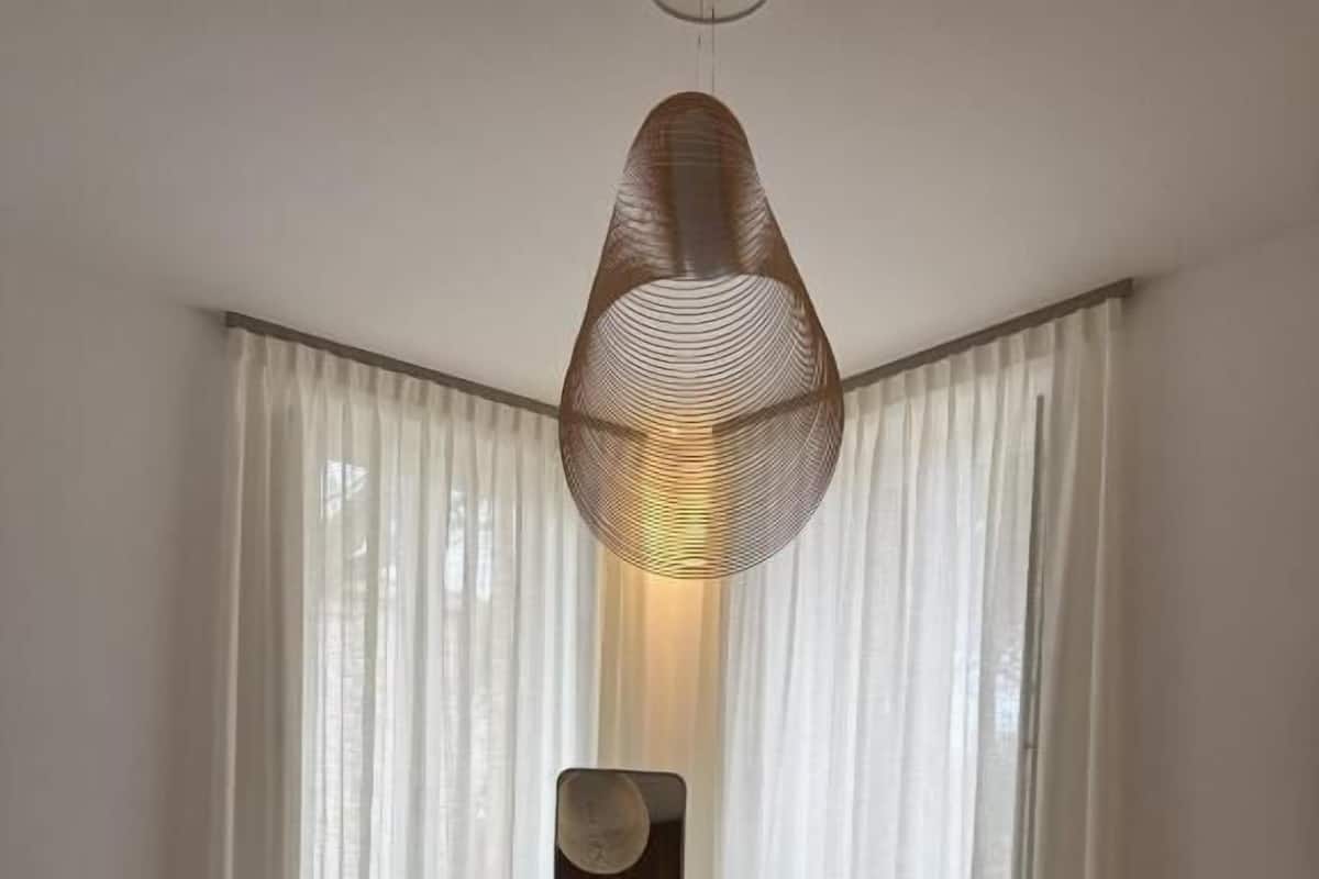 Une chambre à coucher avec un lit, une chaise rouge, un miroir fixé au mur et des rideaux transparents.