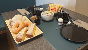 Ein Frühstücksaufbau mit Gebäck, einer Kaffeetasse und Beilagen auf einem Tisch.