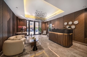 A modern lobby with a reception desk, seating area, and a unique ceiling light fixture. - SADEN-Alsalama (Jeddah)
