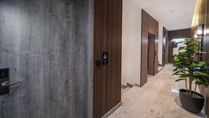 A modern hallway with a digital door lock, wooden paneling, and a potted plant. - SADEN-Alsalama (Jeddah)