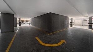 A modern parking garage with a central pillar, clear directional arrows on the floor, and a clean, minimalist design. - SADEN-Alsalama (Jeddah)