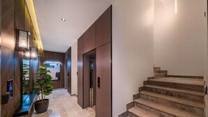 A modern hotel lobby with a marble floor, wooden paneling, a staircase, and a reception desk with a plant. - SADEN-Alsalama (Jeddah)
