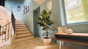 A staircase with a handrail, a potted plant, a framed picture, and a small table with a spherical object. - Mas les murmures (Les Baux-de-Provence)