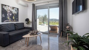 A modern living room with a black sofa, a wooden coffee table, and a large window with curtains. - Marinas villas (Rhodes)
