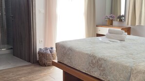 A bedroom with a bed, a television, a mirror, and a shower area.