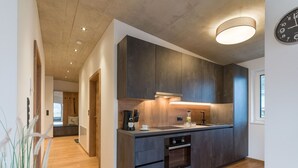 Een moderne keuken met donkere kastjes, een ingebouwde oven en een groot raam.