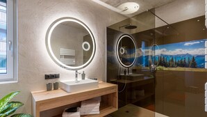 Un baño moderno con un espejo grande, un lavamanos y una ducha.