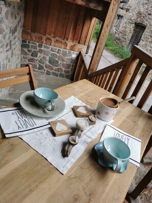A wooden table with a placemat, two blue cups, a mug, and decorative items.