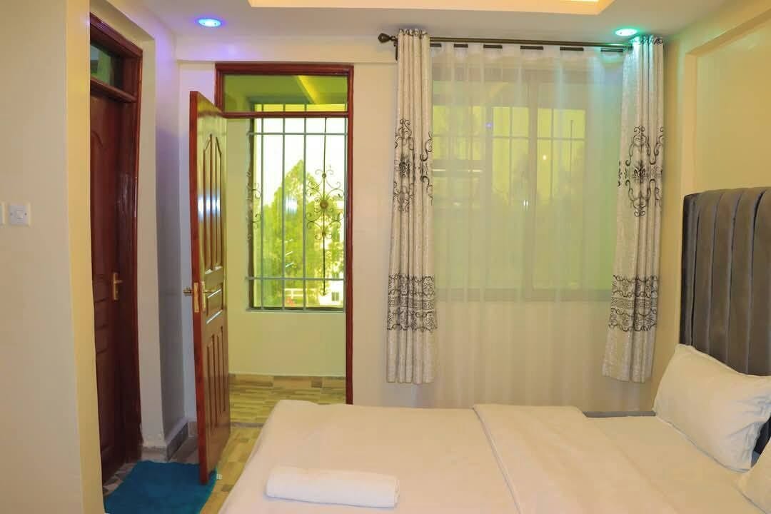 Ein Hotelzimmer mit einem Bett, einem Fenster mit Vorhängen und einer Tür.