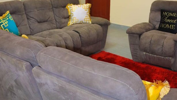 A living room with two grey sofas, a red rug, and a ceiling light fixture. - Lux Suites Taris Apartments Rongo (Rongo)
