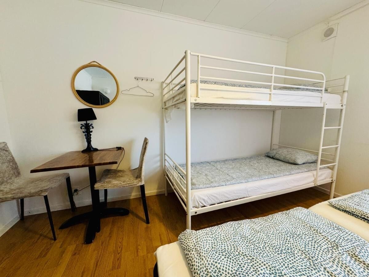 Dormitorio con literas, escritorio, silla y perchero.