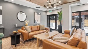 A modern lounge area with leather sofas, a wooden coffee table, and a large mirror on the wall. - Western Dreams w River Views, 2BR, AC (25+) (Calgary)