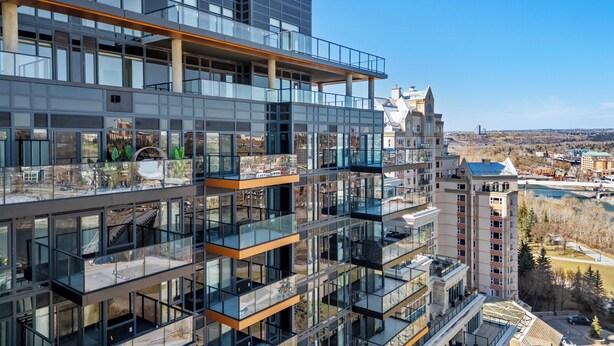 A multi-story building with glass balconies and a view of a historic building in the background. - Western Dreams w River Views, 2BR, AC (25+) (Calgary)