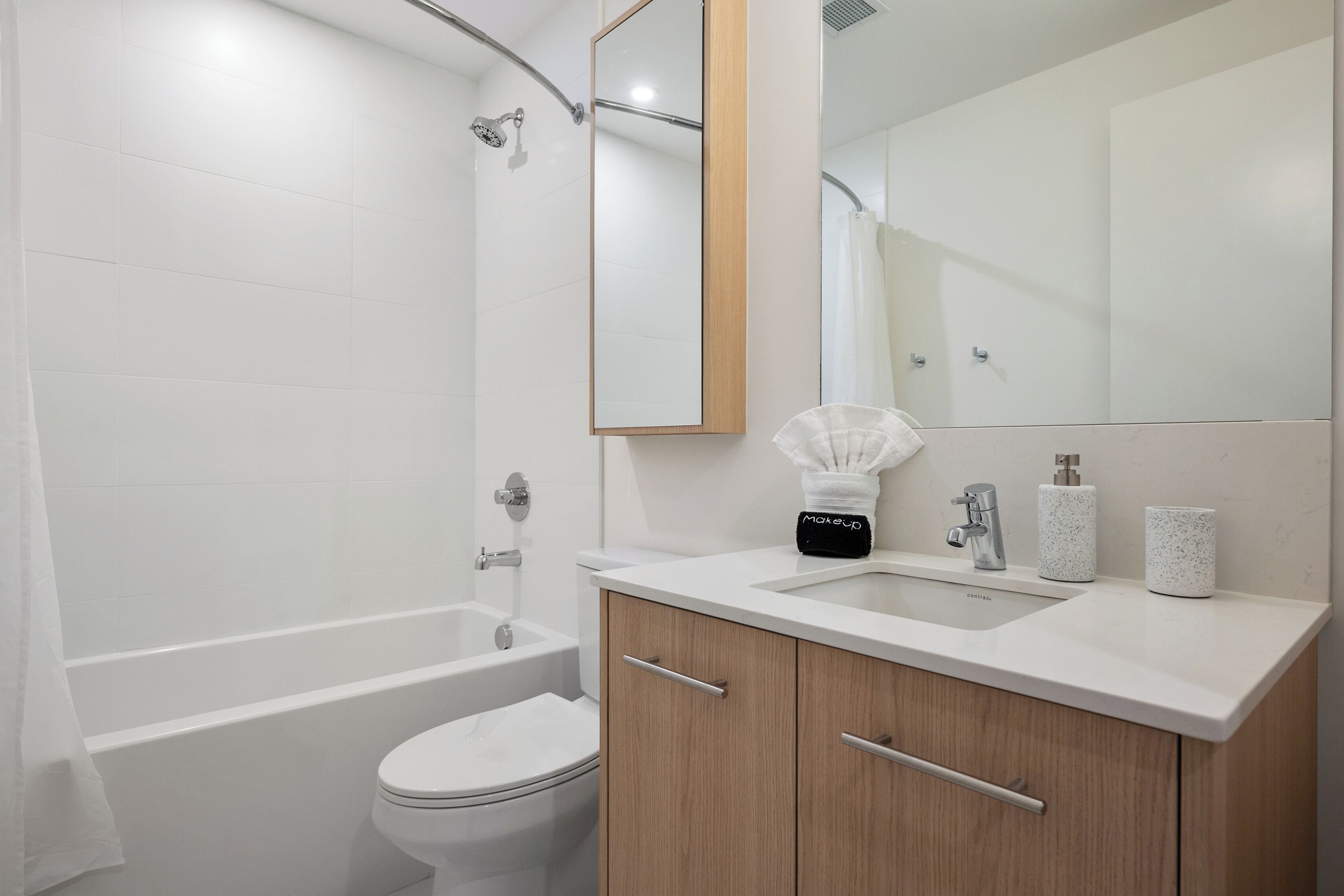 A modern bathroom with a bathtub, toilet, and vanity with a mirror.