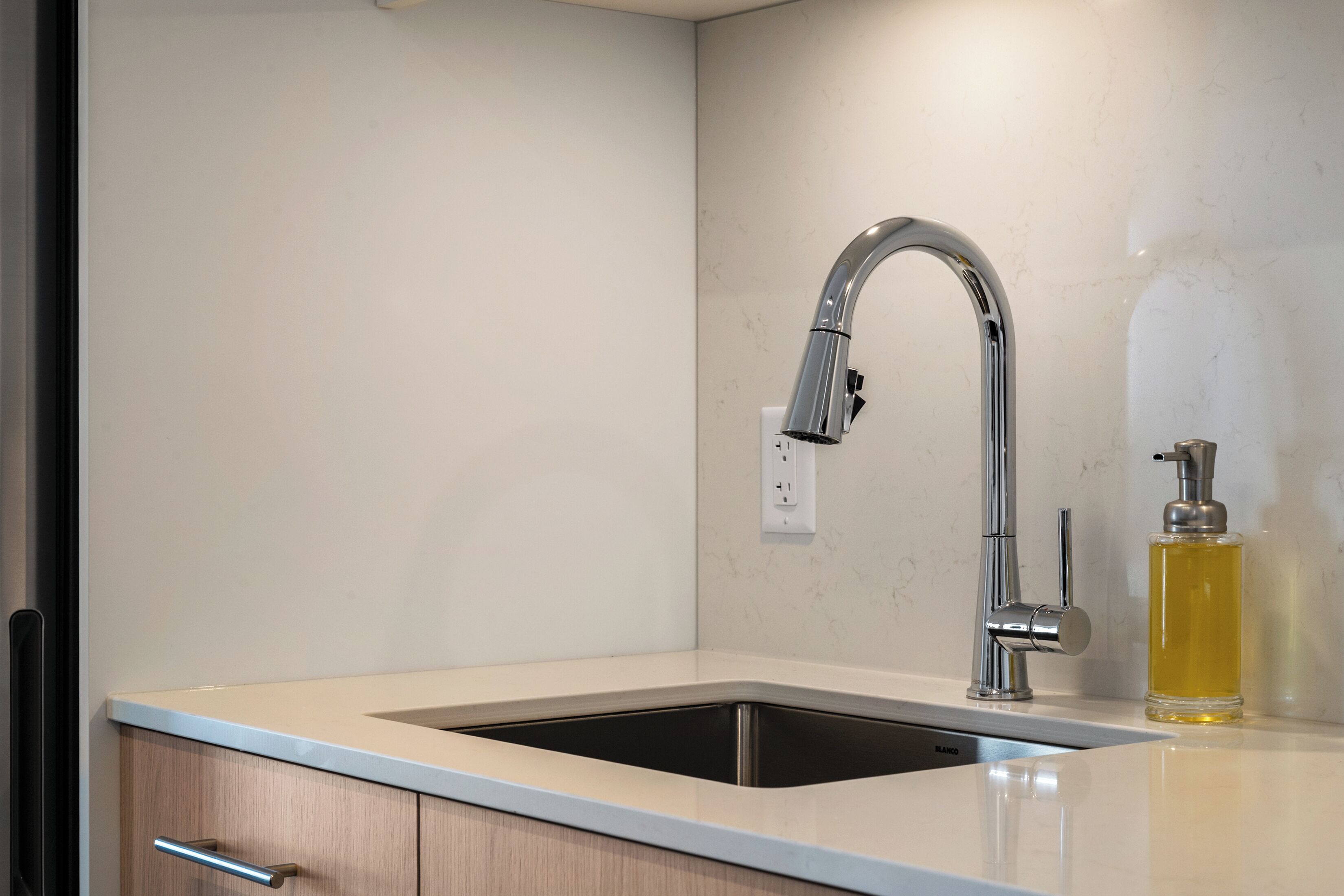 Una cocina moderna con un lavamanos de acero inoxidable, un grifo y un dispensador de jabón.