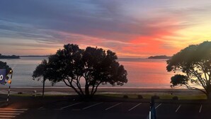 A sunset view over a body of water with trees in the foreground. - Sea Spray Suites - Paihia Beachfront Complex - Unit 5 (Paihia)