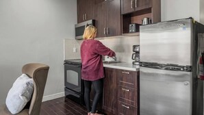 Una cocina moderna con armarios de madera oscura, un refrigerador de acero inoxidable y un horno empotrado.
