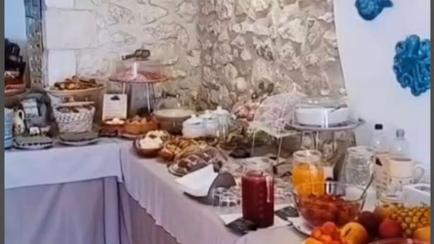 Ein Buffet mit verschiedenen Speisen und Getränken vor einer Wand mit Muster.