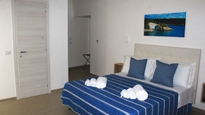 Ein Hotelzimmer mit einem Bett, einem Bild mit einer Küstenansicht und einer Tür.