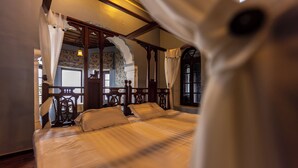 Een slaapkamer met een groot bed, een houten hoofdeinde en een hemelbed.