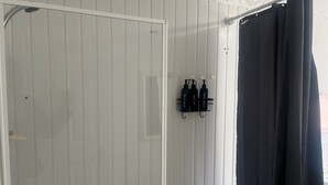 Un baño con ducha, bañera y estante en la pared con artículos de aseo.