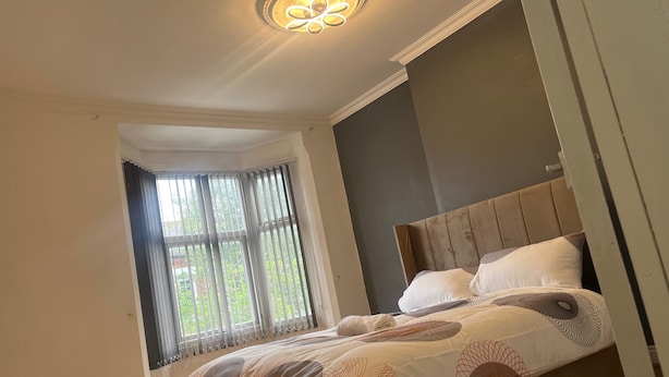 Un dormitorio con cama, ventana con cortinas e iluminación en el techo.