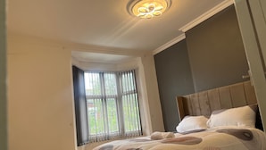 Un dormitorio con una cama grande, una ventana con cortinas y una lámpara de techo.