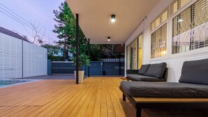 A wooden deck with a sofa and a potted plant.
