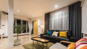 A modern living room with a leather sofa, a wooden coffee table, and a green rug.