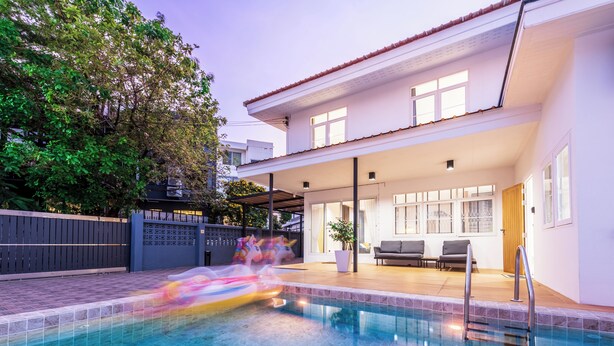 A modern house with a swimming pool, a covered patio, and a fenced backyard.