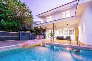 Une maison moderne dotée d’une piscine, d’un patio couvert et d’un jardin clôturé.