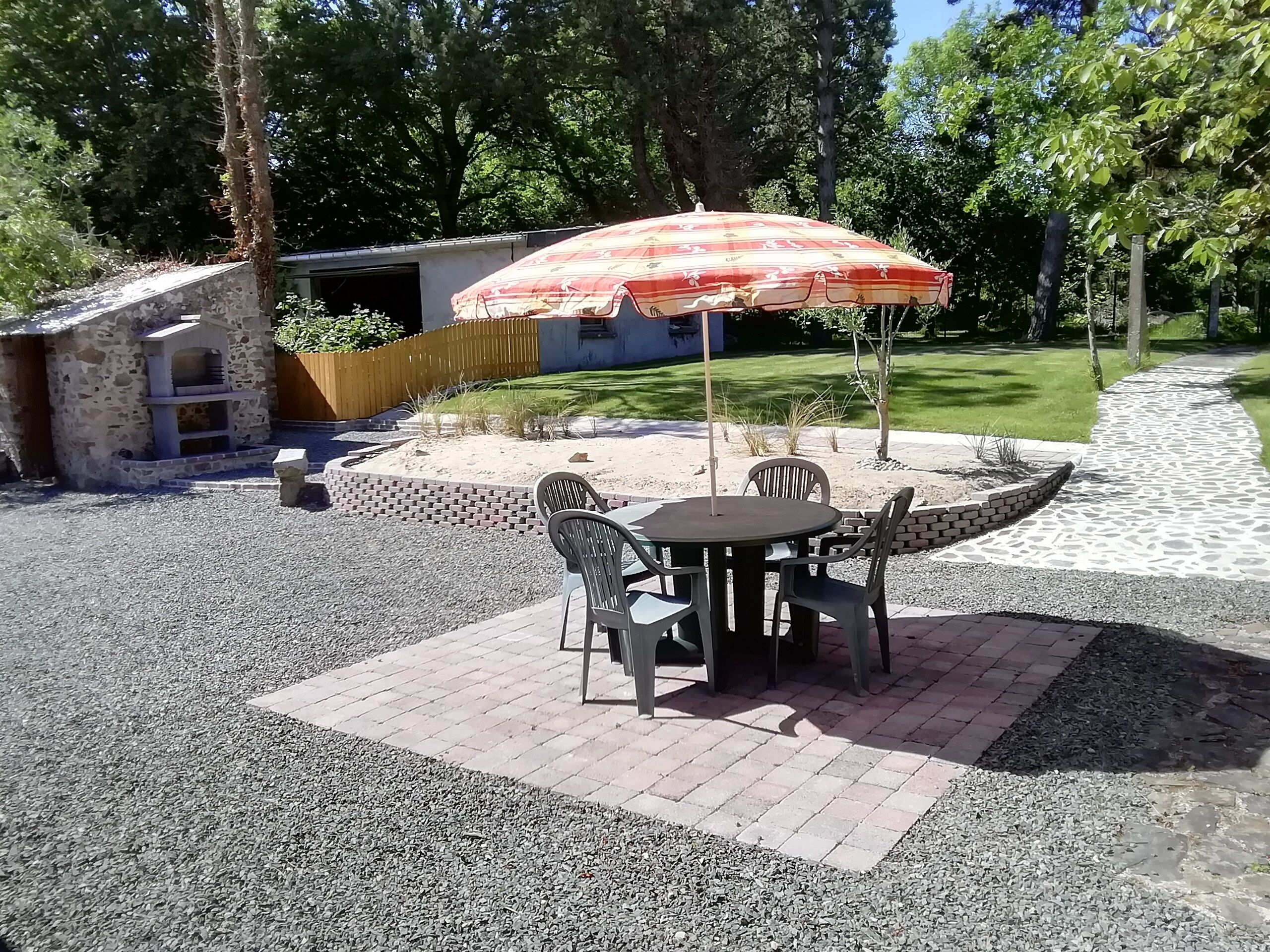 Een terras met een tafel, stoelen en een parasol, met een stenen gebouw op de achtergrond.
