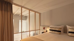 Ein Schlafzimmer mit einer großen Schiebeglas-Tür, einem Bett mit gestreiften Kissen und einem Nachttisch mit Lampe und Vase.