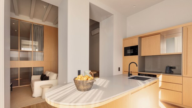 Eine moderne Küche mit einer großen Kochinsel, Holzschränken und einem eingebauten Backofen.