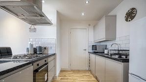 A modern kitchen with a stove, microwave, and cabinets. - Seaside Cottage Escape in Paignton - Sleeps 4 (Paignton)