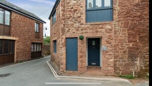 A two-story stone building with a dark blue door and windows, located on a narrow street. - Seaside Cottage Escape in Paignton - Sleeps 4 (Paignton)