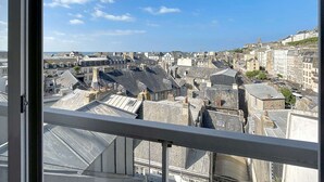 Vista de un paisaje urbano desde una ventana con barandilla metálica.
