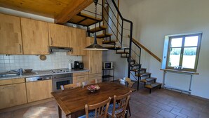 Uma cozinha com armários de madeira, fogão e mesa de jantar com cadeiras.