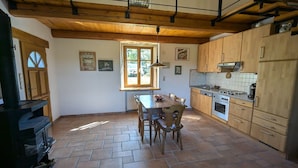Cozinha com mesa e cadeiras de madeira, uma janela e um fogão.