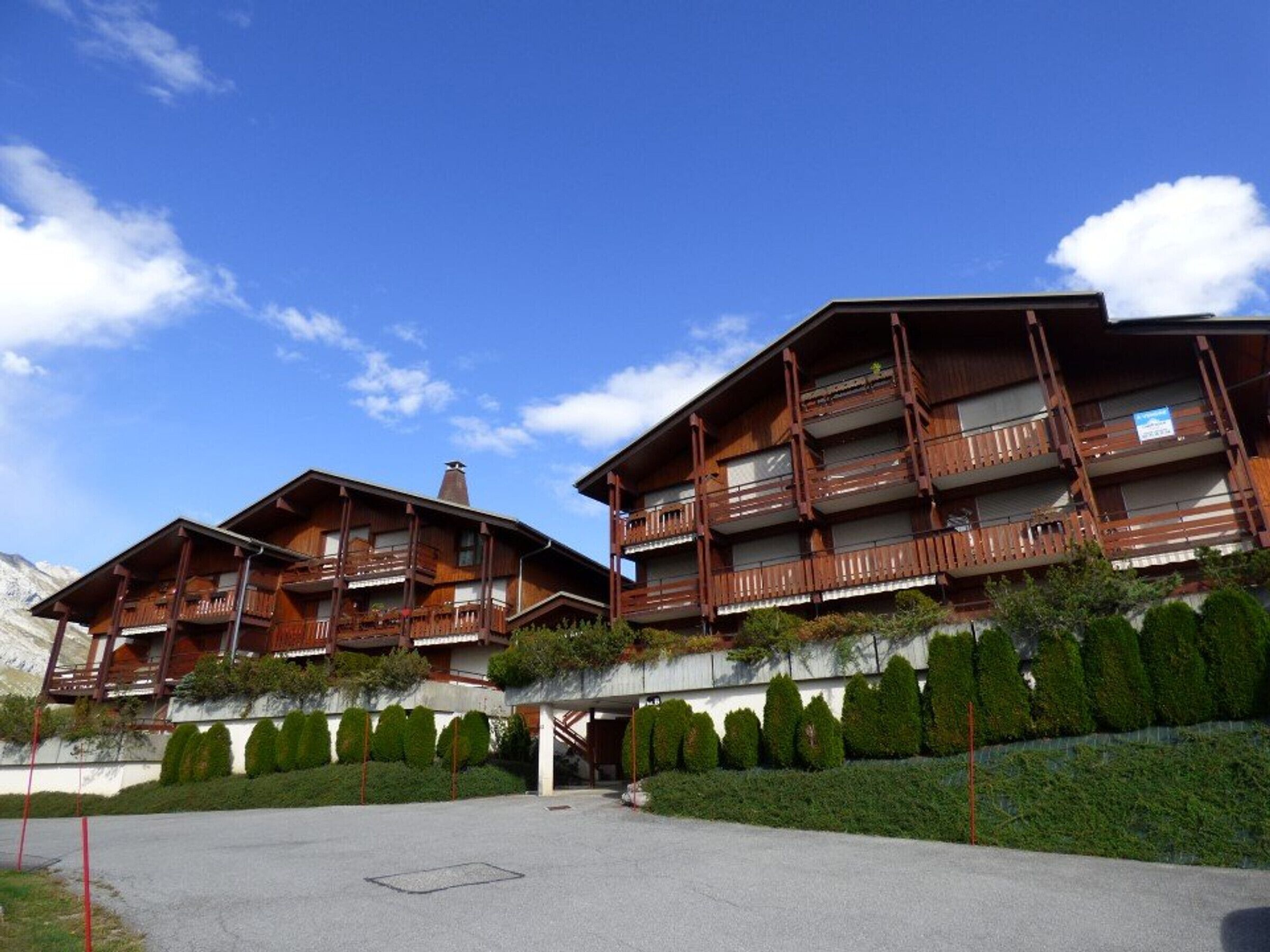Un hôtel de style chalet en bois, doté de nombreux balcons et offrant une vue sur les montagnes.