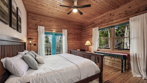 Une chambre dans une cabane en bois, avec un lit, un bureau et une fenêtre avec des rideaux.